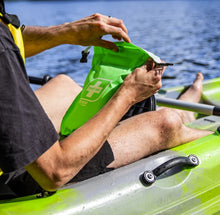 Load image into Gallery viewer, Person in a kayak holding a green dry bag with a logo.