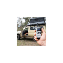 Load image into Gallery viewer, Hand holding a Uniden UH610-MAX with a blurred background of a vehicle and trees

