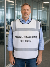 Load image into Gallery viewer, Man wearing a white safety tabbard style vest with 'COMMUNICATIONS OFFICER' text in an office setting
